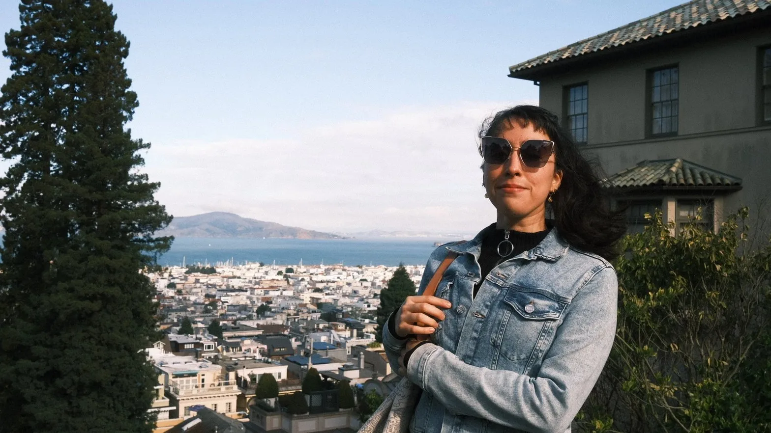 Lucero in denim jacket overlooking city skyline