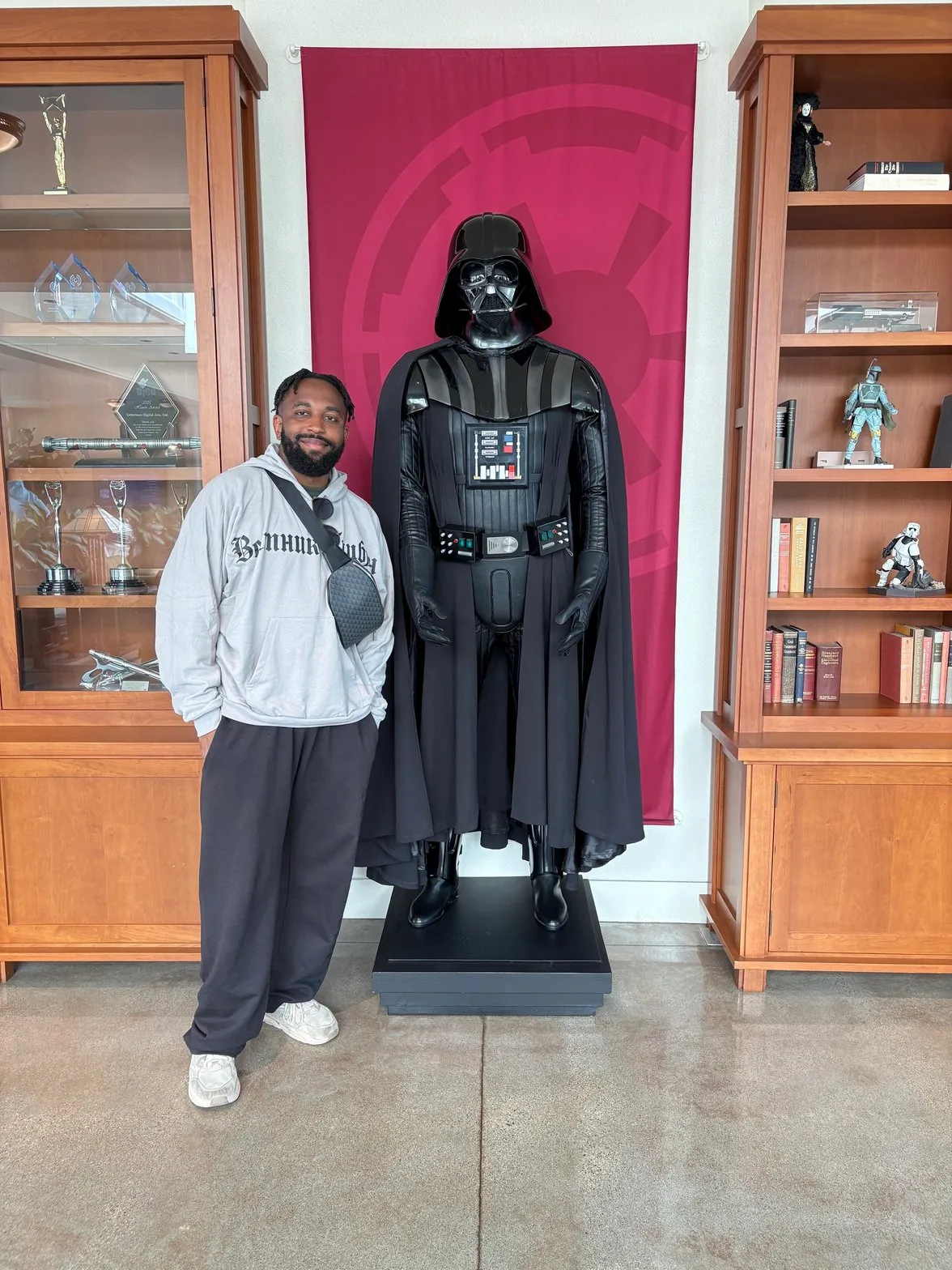 Uko standing next to Darth Vader figure in office